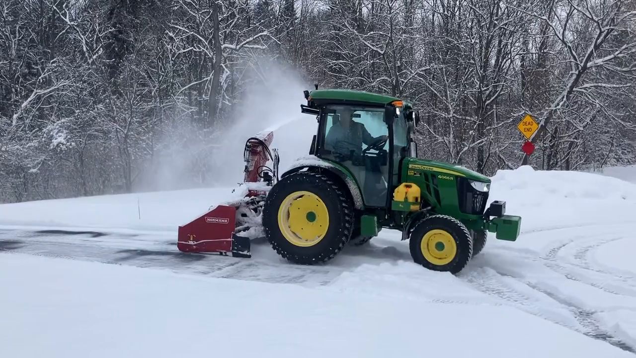 RAD Snowblowing John Deere 4066R tractor with a Normand snowblower clearing a snowy driveway