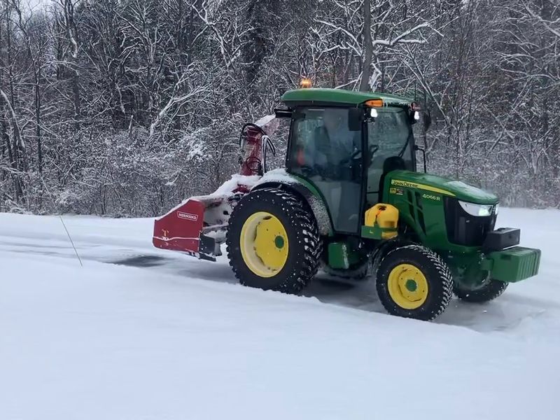 John Deere 4066R tractor with an inverted Normand snowblower clearing snow